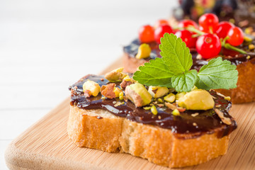 Sandwiches with chocolate paste, pistachio nuts and fresh berries on a wooden serving Board.