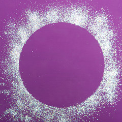 Christmas background with free space. A simple background of a circle filled with silvery artificial snow on a purple wooden background.
