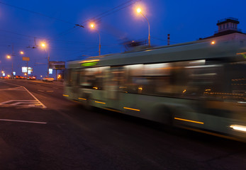 Naklejka na ściany i meble The motion of a blurred trolleybus in the street in the evening.