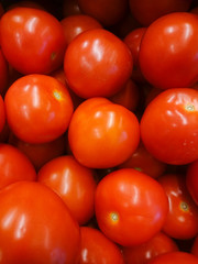 Vegetables are full of vitamins. Fresh and ripe tomatoes in a basket on a supermarket shelf