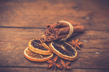 Spices for mulled wine: cinnamon sticks, star anise, slices of orange on a wooden background.