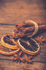 Spices for mulled wine: cinnamon sticks, star anise, slices of orange on a wooden background.