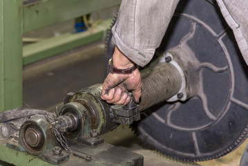 A mechanic repairs a machine in a factory.