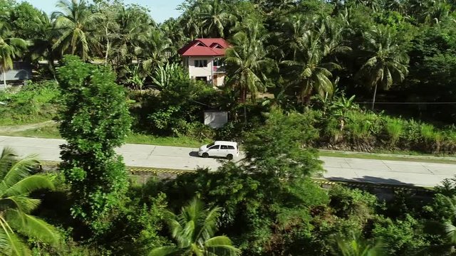 Aerial view of white car driving on road in Carcar City, Philippines.