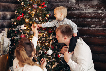 Portrait of loving dad with daughter on his shoulders decorating beautiful Christmas tree with toys...