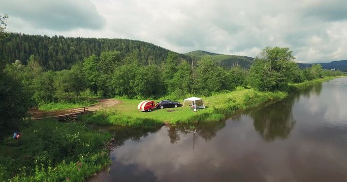 Family Car Camping with Residential Trailer and Tent on the River Coast in a Wild Bautiful Place in Ural Mountains - Aerial Drone View