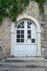 Old, glass, paneled white wooden door in the old building.