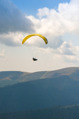 Paraglider fly over a mountain valley on a sunny summer day. Paragliding in the Carpathians in the summer.