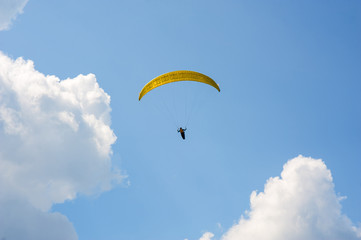 Paraglider is flying in the blue sky against the background of clouds. Paragliding in the sky on a sunny day.