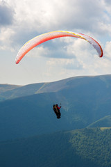 Paraglider fly over a mountain valley on a sunny summer day. Paragliding in the Carpathians in the summer.
