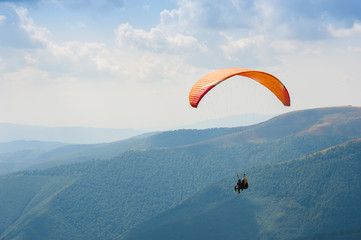 Paraglider fly over a mountain valley on a sunny summer day. Paragliding in the Carpathians in the summer.