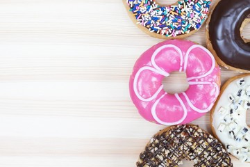 assorted donuts pink and chocolate frosting, sprinkles donuts Colorful variety and Variety of flavors on a wooden background. top view. space empty copy leave a message.