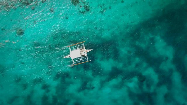 Aerial view of single filipino fishing boat sailing in turquoise water near Lapu-Lapu city, Philippines.