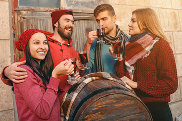 Smiling european men and women during party photoshoot. The guys posing as friends at studio fest with wineglasses with hot mulled wine on foreground.