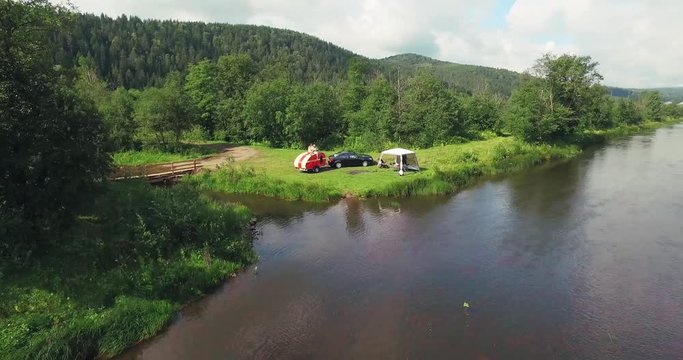 Family Car Camping with Residential Trailer and Tent on the River Coast in a Wild Bautiful Place in Ural Mountains - Aerial Drone View