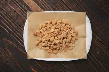 White plate with roasted peanuts as beer snack