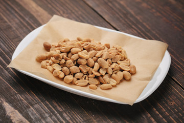 White plate with roasted peanuts as beer snack
