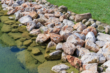 Fototapeta na wymiar water stones and grass, the shore of the pond