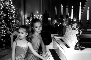 two sisters on a Christmas night at a white grand piano.