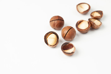 Macadamia nuts are unshelled with shells on white background