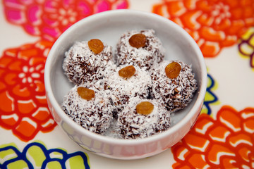 Fototapeta na wymiar Raw Organic Dessert. Vegan chocolate balls with coconut and raisins on top