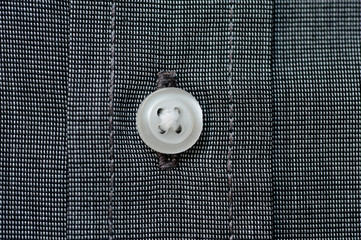 Texture of dark gray shirt fabric with white buttons close-up shot