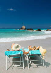 Couple on sunbeds relaxing at the beach in Lefkada