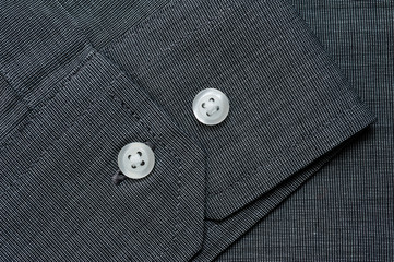 Texture of dark gray shirt fabric with white buttons close-up shot