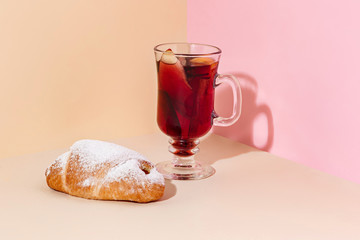 Mulled wine in glass with cinnamon stick, christmas cake on on the glass table. Winter concept