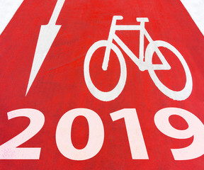 2019 New Year White graphic signs of arrow with bicycle symbol on a red bike path on the road in the city for new achievement in future