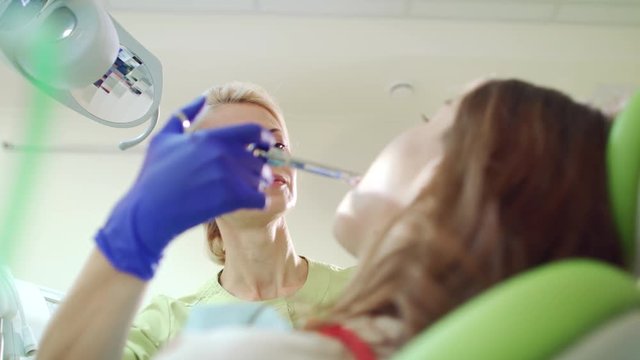 Dentist doing anesthetic injection in sick tooth. Female stomatologist using medicine syringe. Woman doctor treating patient in dentist office. Stomatology anesthesia