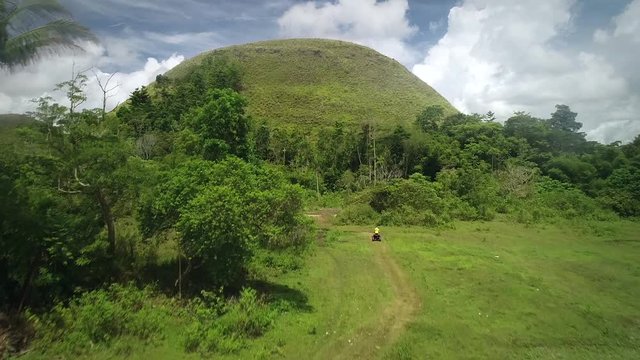 Aerial view two quadricycles doing trail next of Chocolate Hills Complex, Batuan, Philippines.