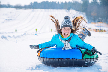 young smiling girl ride sleigh snow tubing hill winter activity