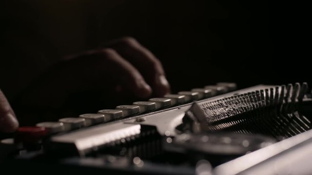 Extreme close up of hands typing on an old dusty vintage typewriter in slow motion