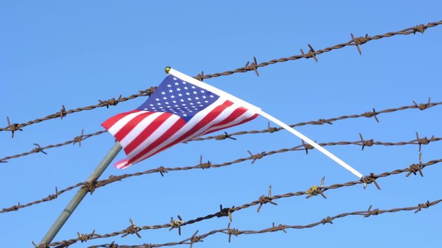 American flag waving on barbed wire fence 4K