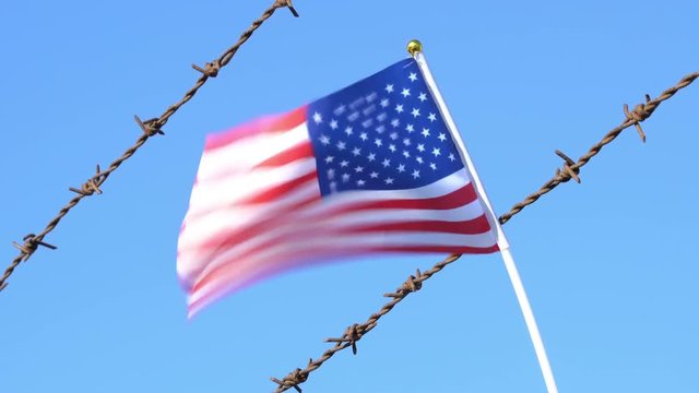 USA flag waving on barbed wire fence 4K