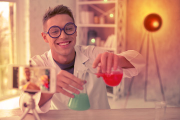 Smiling experimenter making a video about chemistry