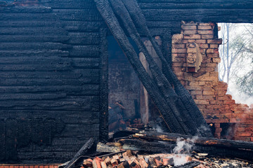 charred wooden parts of a burnt house in countryside