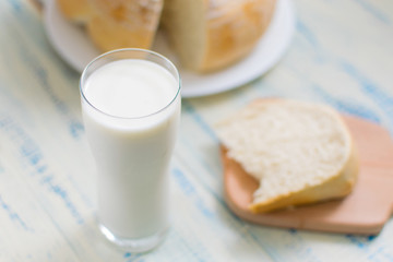 A glass of milk and white bread on a wooden background.