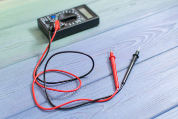 Electronic multimeter to measure the current on a wooden background.