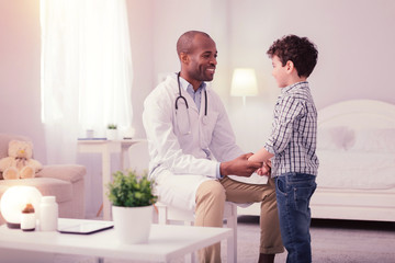 Fototapeta premium Joyful friendly doctor holding his patients hand