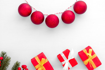 Christmas and New Year background.  Christmas gifts boxes, fir branch, red berry and red balls on white paper. Creative flat lay, border and  top view design