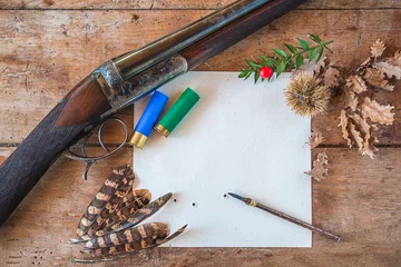 Photo sur Plexiglas Chasser Beautiful hunting season still life/vintage hunting rifle, cartridges, vintage pen on the target with traces of bullets, pheasant feathers on old wooden background