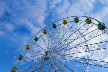big Ferris wheel against blue sky with clouds