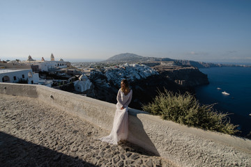 The beautiful blond hair young women bride blue in a wedding white long sexy dress on Santorini in Greece