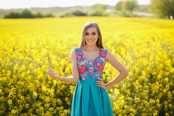 Naklejka na ściany i meble Blode girl posing in blue dress in yellow field