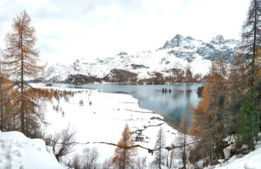 First autumn snowfall on the lake in Engadine valley Switzerland near the Maloja pass