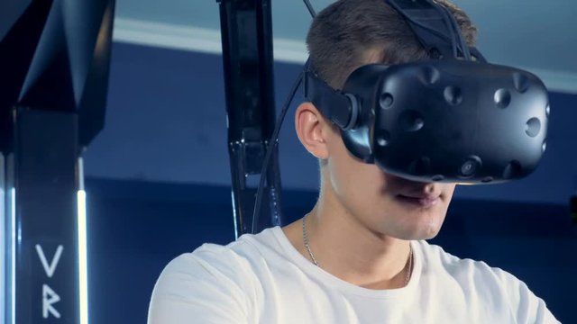 A young man is wearing virtual reality headset and playing 360 virtual reality game.