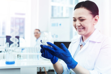 Cheerful female biologist looking at the heart model