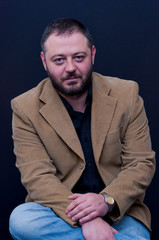 Fototapeta premium Portrait of sitting man with yellow jacket and black shirt